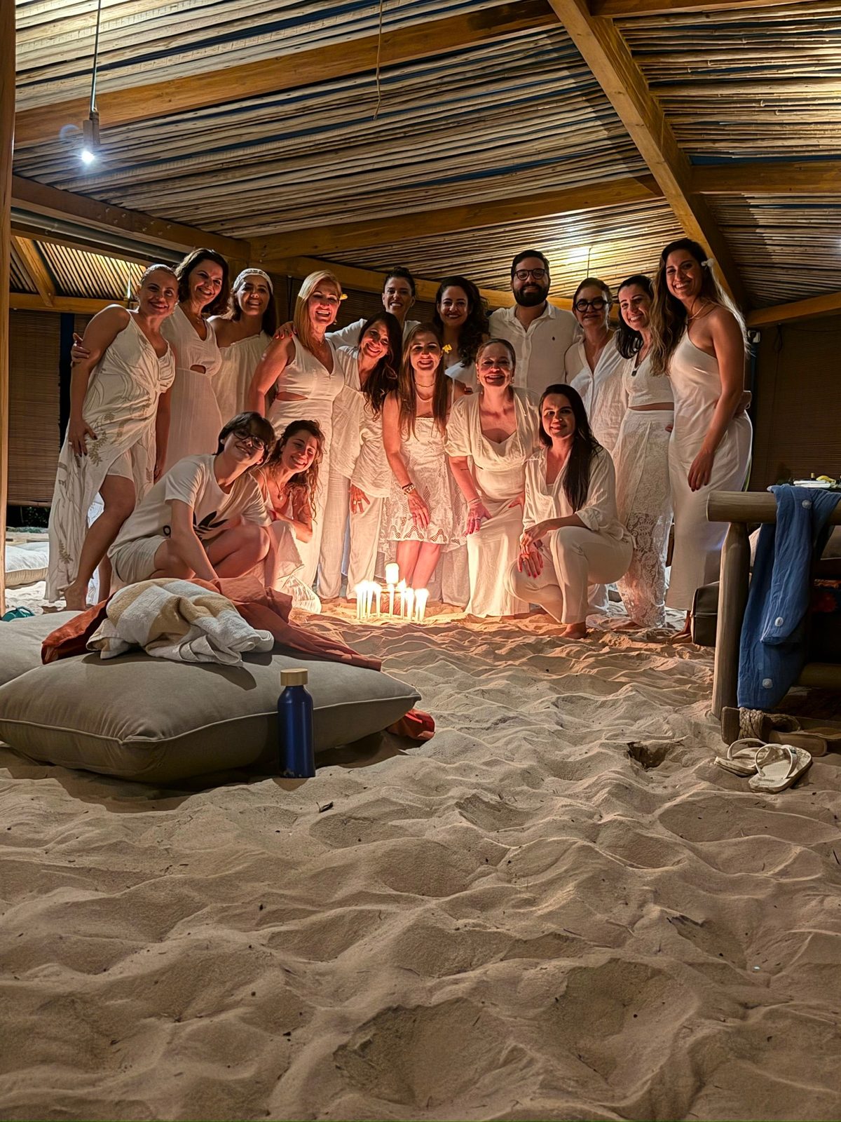 Grupo reunido na areia com velas